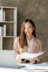Asian woman using laptop for mathematical finance on table, tax, report, accounting, statistics and...