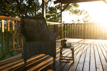 Balcony of log cabin with armchair and mug of coffee on sunny day