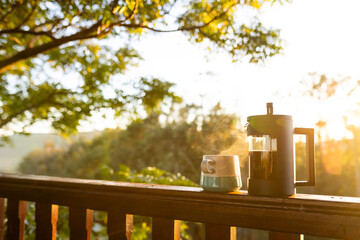 Balcony of log cabin with coffee press and coffee mug on sunny day