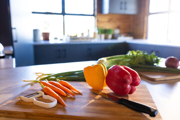 Organic vegetables on cutting board and knife in sunny kitchen in log cabin