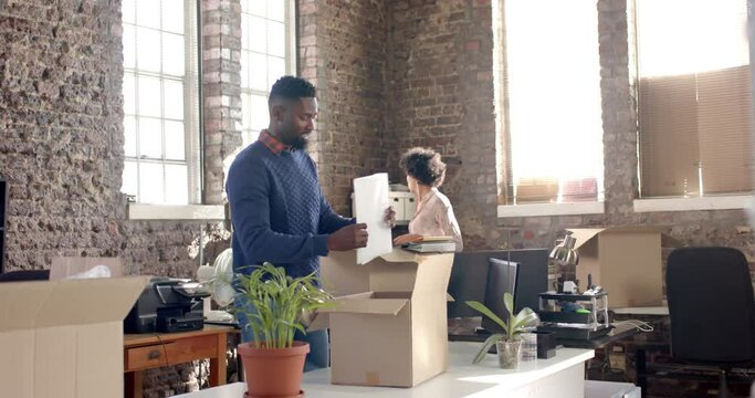 Diverse colleagues unpacking boxes with documents and office items in creative office in slow motion