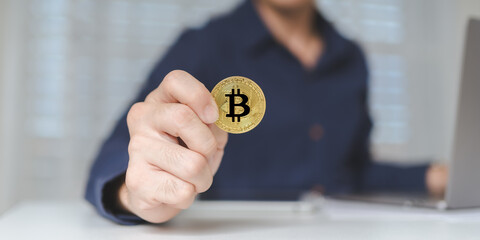 Bitcoin Cryptocurrency investment concept. Trader or investor hand holds Bitcoin Cryptocurrency gold coins. Businessman shows Bitcoin Cryptocurrency on hands while using laptop for trading. Banner. - 620362410