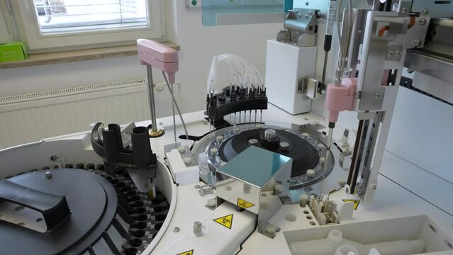Medical analyzer pipetting samples from test tube and putting them in testing chambers on a rotary disk on a modern biochemical machine for human blood testing