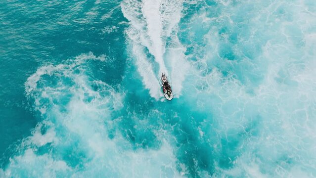 Cinematic aerial view of dangerous surfing site on Hawaii. Shore crew delivering surfers on surfboards to waves. Overhead lifeguards riding jet ski to pick up surfers in stormy ocean waters at sunset