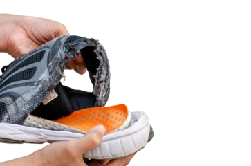 Hand holding an old, broken black shoe behind the heel of the shoe on transparent background