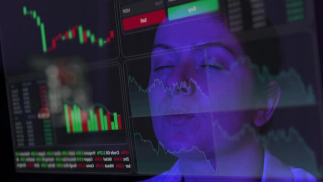 A woman looks at a virtual screen with a HUD menu in the dark. Stock charts. Broker terminal. 