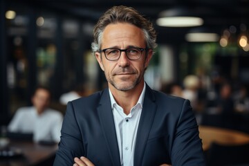 Happy middle-aged businessman standing in arms at work