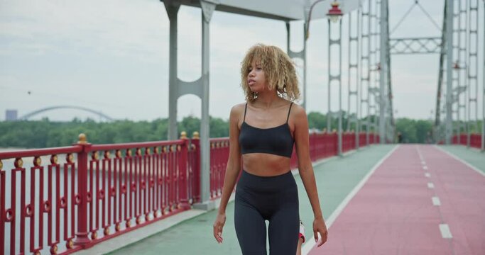 Fit young African American woman warming up and stretching before jogging on the bridge