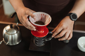 Fototapeta na wymiar Slow bar coffee concept, Closeup hand of barista preparation ground coffee into dripper v60 for making coffee filter.