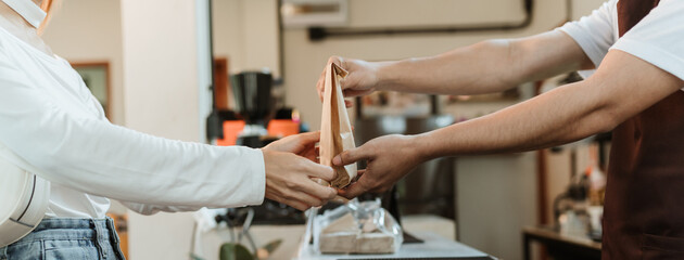 Waitress giving paper bag to customer at coffee shop. SME business coffee shop concept. - obrazy, fototapety, plakaty