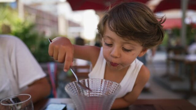 Little boy eating ice cream dessert. Cute child eats strawberry icecream at restaurant