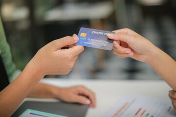 Asian woman in green shirt handing credit card to store clerk