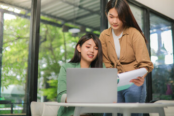 Two Asian women are consulting in the workplace. and see the work in the notebook
