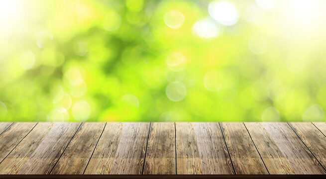 Wooden table top with natural green blurred bokeh background or various leaves, fresh bright sunlight, product empty concept.	