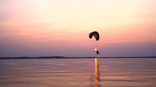 Parachute flight over the sea at sunset