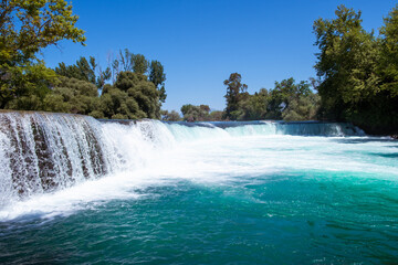 Fototapeta premium Manavgat waterfall Manavgat River is near the city of Side, 3 km north of Manavgat in Turkey. A wide stream of water falls from a low height.