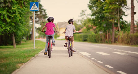Two boys riding on their bicycles along an asphalt road