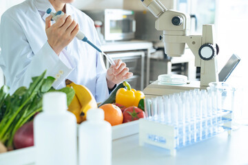 顕微鏡で野菜の成分を観察する若い研究者　管理栄養士