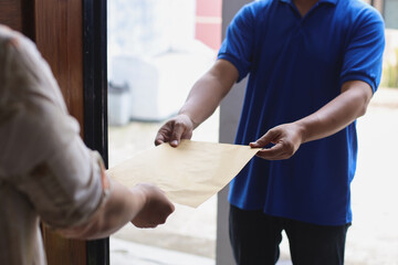 Delivery service man in blue uniform giving mail to l customer at home. Express delivery and documents delivery concept. 