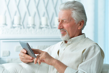 smiling senior man using tablet at home