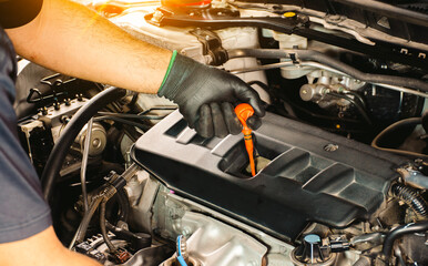Auto mechanic checking the oil level by dipstick of a car engine. Car service