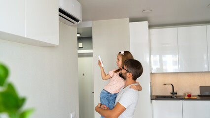 Happy family adjust comfortable temperature of air conditioner using remote control. - obrazy, fototapety, plakaty