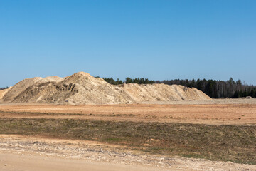 Giant pile of sand against the blue sky. Sand extraction mine.