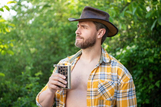 masculine cowboy with flask outdoor. masculine cowboy with flask wear hat. image of masculine cowboy