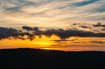 Fototapeta na wymiar A beautiful orange sunset with a silhouette of the mountains
