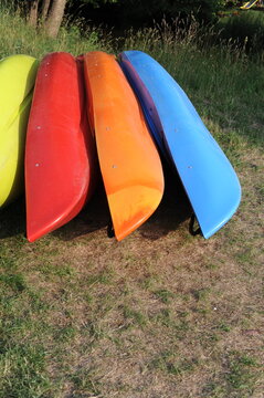 kayaks stacked in a row on a green meadow on a sunny summer day