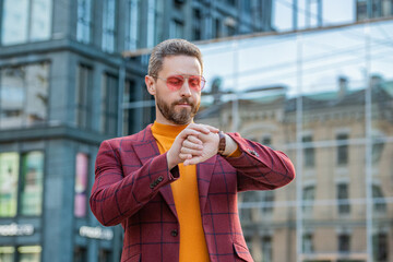 punctual man in jacket and glasses check time outdoor. punctual man check time in the street.