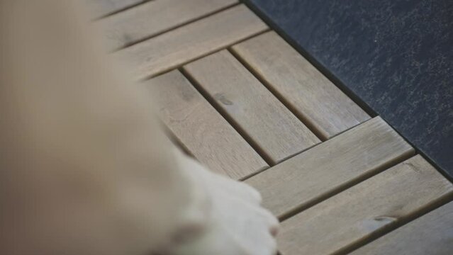 Person Installing Wood Deck Tiles At The Garden Yard. Close up