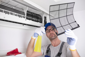 Service guy cleaning and maintaining air condition unit.