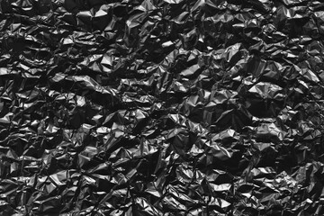 Shiny black foil texture background, pattern of wrapping paper with crumpled and wavy.