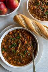 Bowls with delicious lentil stew and bread on the table