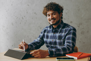 Smiling fun young graphic designer employee business Indian man wear casual blue checkered shirt...