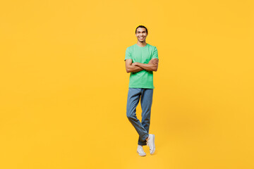 Fototapeta na wymiar Full body young man of African American ethnicity he wears casual clothes green t-shirt hat hold hand crossed folded look camera isolated on plain yellow background studio portrait. Lifestyle concept