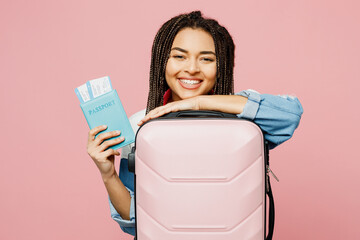 Traveler woman wear casual clothes hold suitcase passport ticket isolated on plain pastel pink background studio. Tourist travel abroad in free spare time rest getaway Air flight trip journey concept