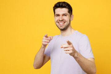 Young smiling caucasian man he wears light purple t-shirt casual clothes point index finger camera on you motivating encourage isolated on plain yellow background studio portrait. Lifestyle concept.