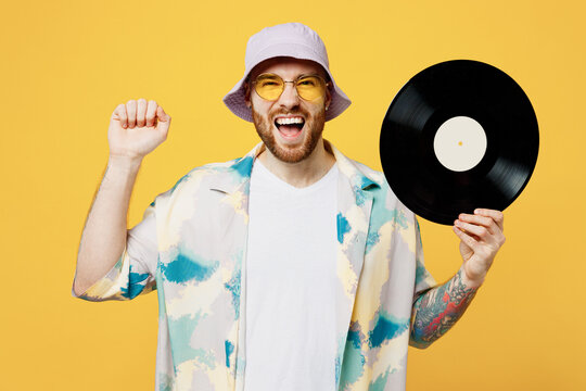 Young excited happy satisfied amazed cool DJ man wear blue shirt white t-shirt casual clothes hold in hand retro vintage music plate clench fist isolated on plain yellow background. Lifestyle concept.