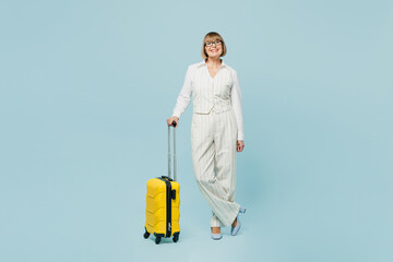 Traveler employee business woman wears classic suit formal clothes hold bag isolated on plain blue background. Tourist travel abroad in free spare time rest getaway. Air flight trip journey concept.