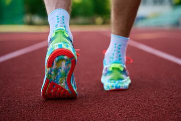 Male sportsman wearing running shoes at stadium track preparing to training. Sport and fitness runner athlete training at stadium