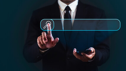 Businessman is using smartphone and pointing or touching search bar against dark blue background.