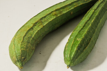 Two whole oyongs or gambas or luffa gourd isolated on a white background.