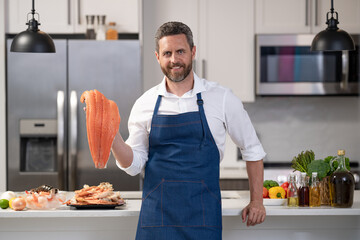 cheerful chef man cooking fish salmon. chef man cooking fish in the kitchen.