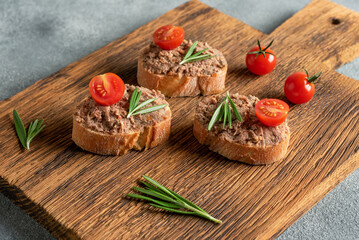 Toast with liver pate on a wooden board. Open sandwich with liver pate. Side view, selective focus.