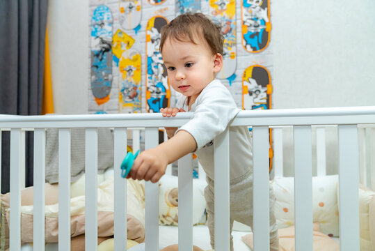 Little kid standing in a bed. Baby playing in the crib.
