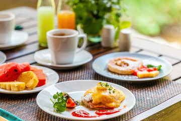Healthy breakfast with delicious tropical fruits, eggs and freshly brewed coffee served on a table in a Thai resort.