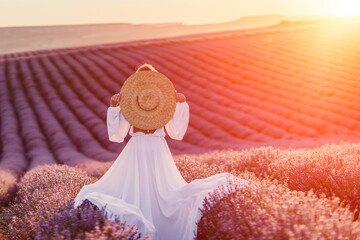 Happy woman in a white dress and straw hat strolling through a lavender field at sunrise, taking in...