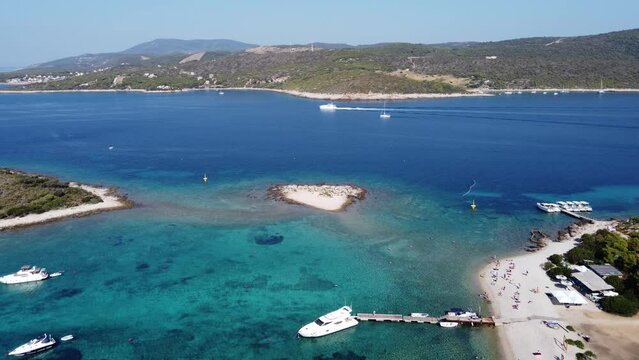 People relaxing at Blue Lagoon Beach of Veliki Budikovac island with their Yachts anchored at Archipelago bay. Aerial